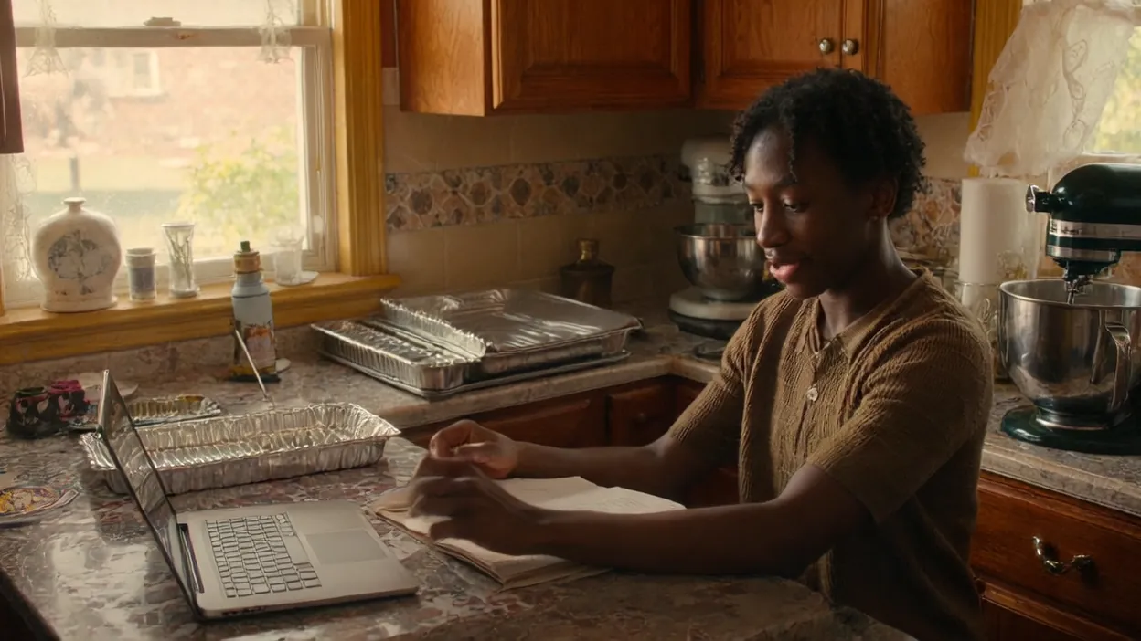 A caterer reads through notes at her kitchen counter beside a laptop and trays.